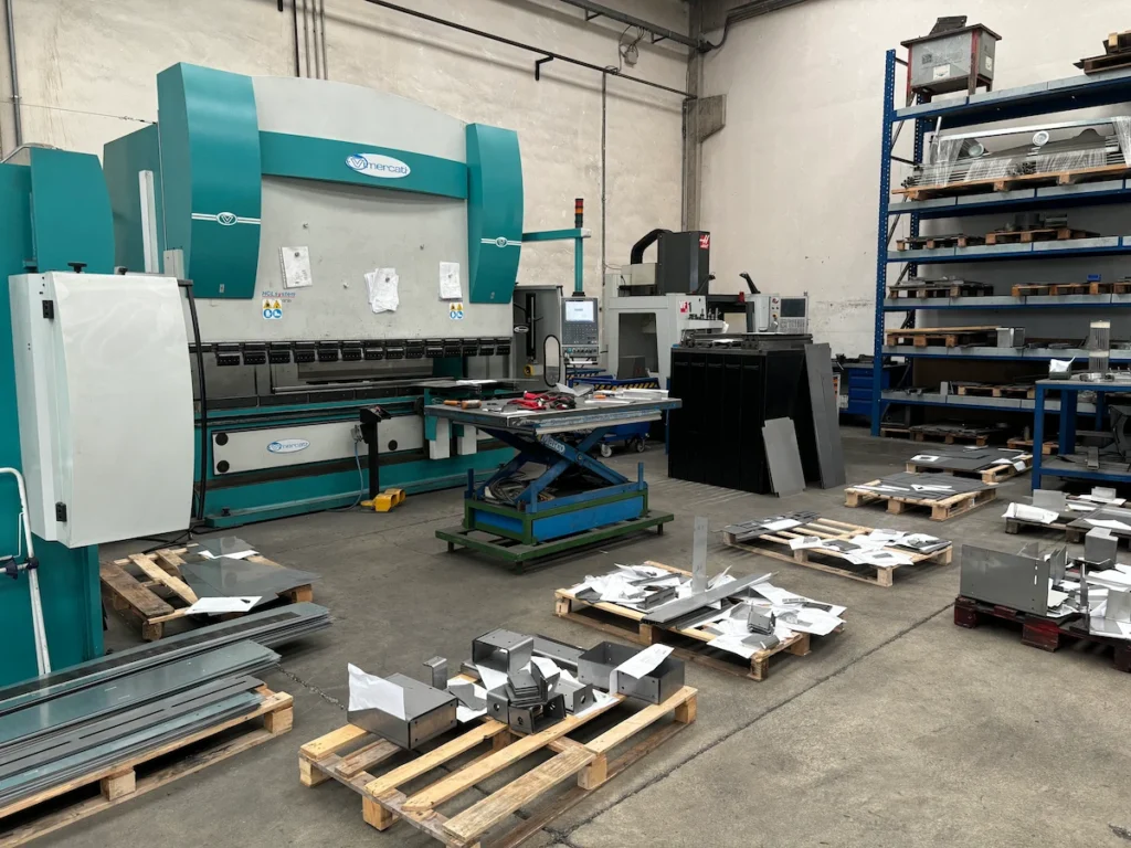 Stanza interna dell'officina industriale FDZ con macchinari, componenti metallici e scaffalature organizzate