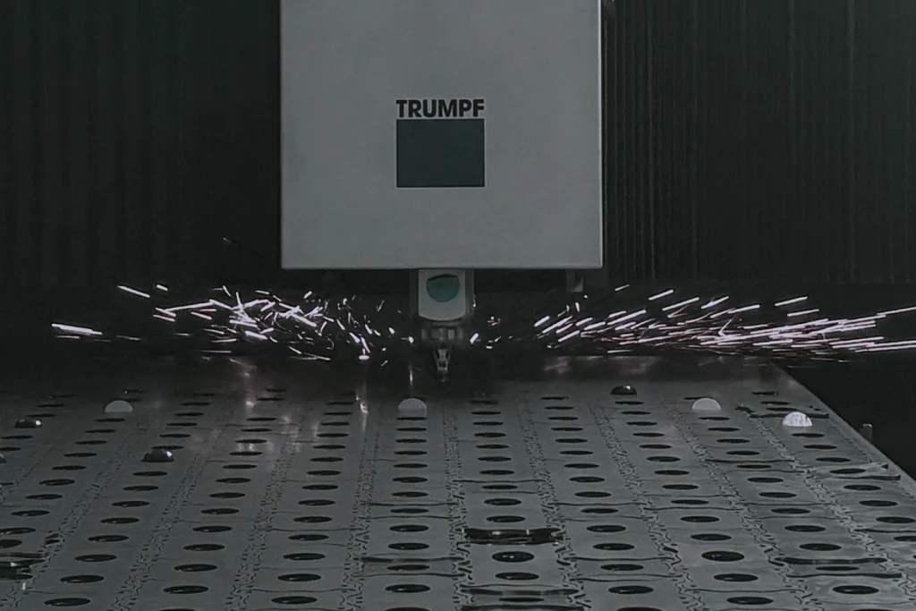 Macchina Trumpf per la lavorazione dei metalli che emette scintille durante il taglio di una lamiera con fori circolari